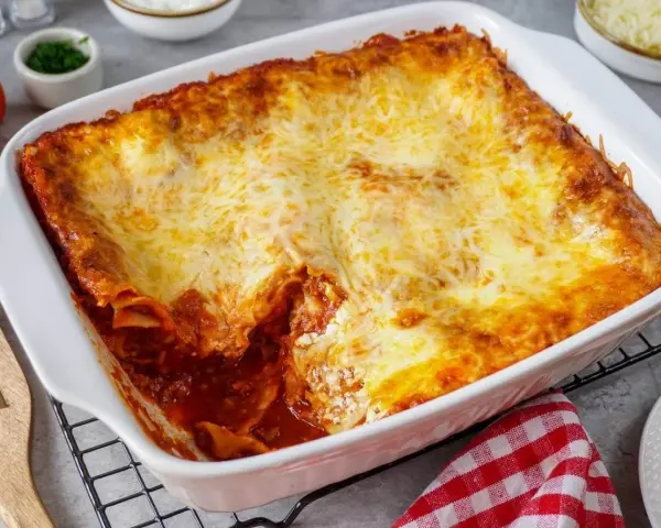 Herzhafte Lasagne mit Schmand und goldbraun überbackenem Käse in einer weißen Auflaufform.