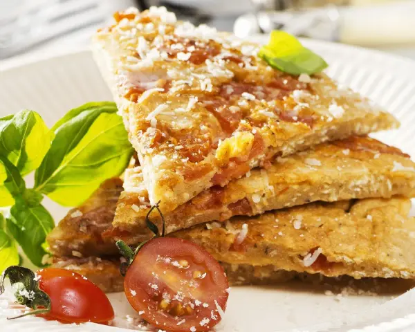 Herzhafte Hauptspeise: knusprige Eierkuchen-Schnitten mit Tomaten und Parmesan, garniert mit Basilikum und Kirschtomaten.