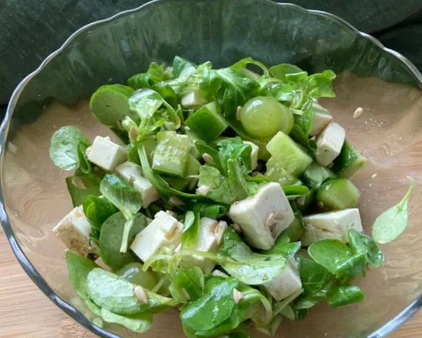 Erfrischender weintrauben feta salat mit Gurkenwürfeln und Sonnenblumenkernen in einer Glasschüssel.