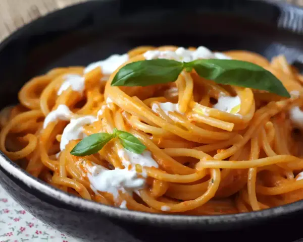 Spaghetti mit cremiger Tomatensoße und frischer Burrata, garniert mit Basilikum. Ein Genuss für alle Liebhaber von Pasta.