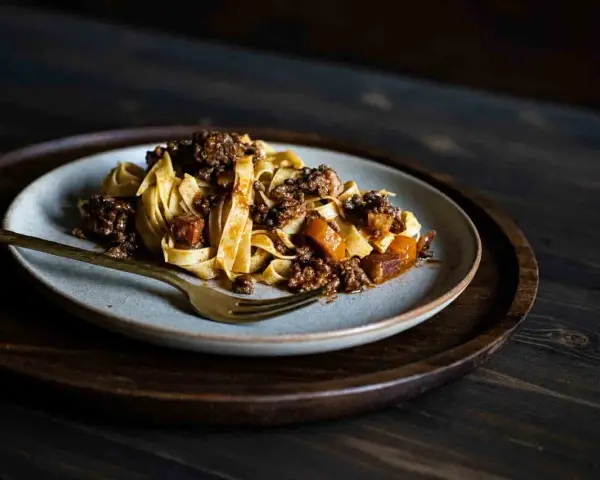Teller mit breiten Bandnudeln und herzhafter Hackfleischsauce, eine köstliche spaghetti bolognese.