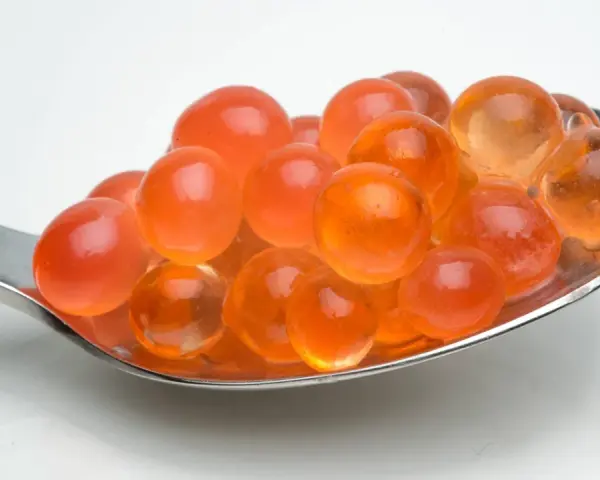 Löffel voller leuchtend oranger Kugeln, die aussehen, als könnte man sie leicht selber machen. Tapioka perlen selber machen ist einfacher als gedacht!