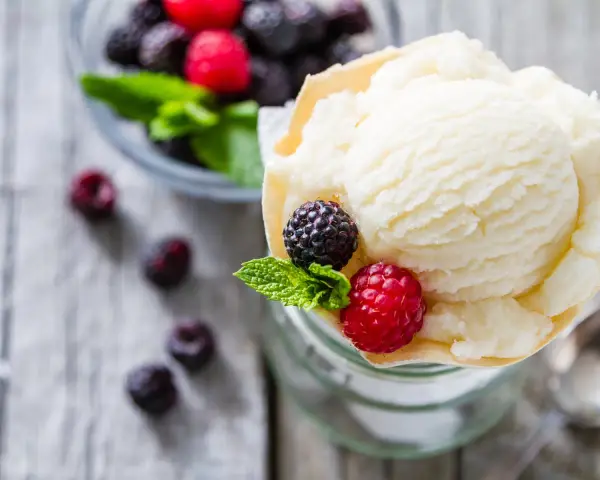 Cremiges Joghurteis selber machen, garniert mit frischen Beeren und Minze. Ein Genuss für heiße Tage!
