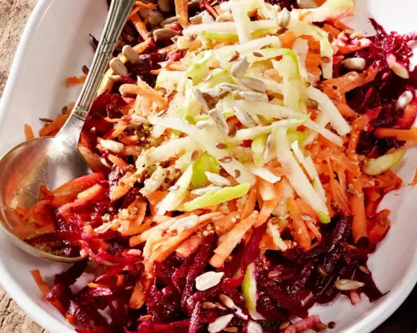 Bunter Salat aus geraspelter roter Bete, Karotten und Apfel, garniert mit Sonnenblumenkernen.