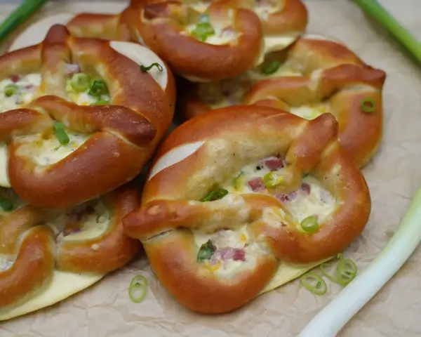 Herzhafte Brezeln gefüllt mit Käse und Speck, perfekt als partyrezepte aus dem ofen zum vorbereiten. Mit Frühlingszwiebeln garniert.