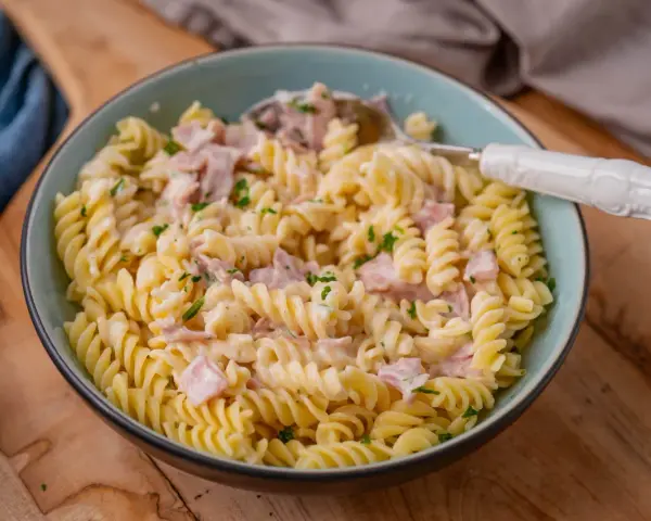 Fusilli-Nudeln mit einer cremigen **Schinken Sahne Sauce**, garniert mit Petersilie. Ein köstliches Gericht, das zum Genießen einlädt.