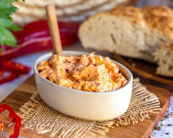 Cremiger Ajvar Feta Dip mit frischer Petersilie und Paprika, serviert mit rustikalem Brot.