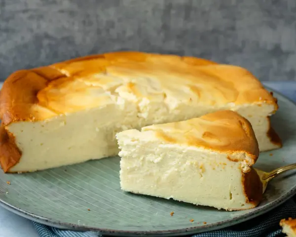 Saftiger Kuchen mit 250g Quark und Vanillepudding, goldbraun gebacken, auf einem Teller mit einem Stück daneben.