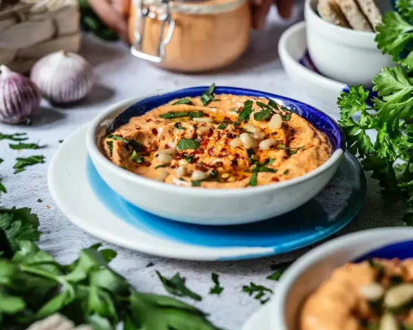Cremiger Feta Paprika Dip mit Pinienkernen und frischer Petersilie, garniert mit Chiliflocken. Perfekt zum Dippen!