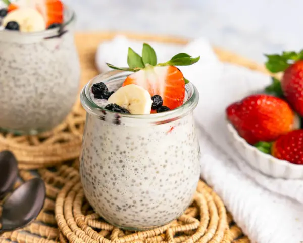 Leckerer Chia Pudding mit Milch, garniert mit Erdbeeren, Bananen und Blaubeeren. Ein gesunder Genuss!