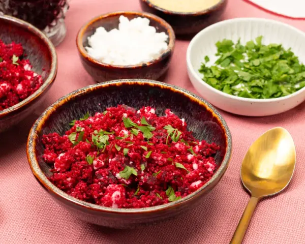 Rote Bete Couscous Salat mit Feta und Petersilie, garniert mit Zitronenspalte.