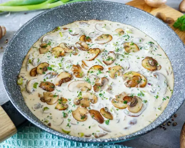 Cremige champignon rahm sauce in einer Pfanne, garniert mit frischer Petersilie. Ein Genuss für jeden Pilzliebhaber!