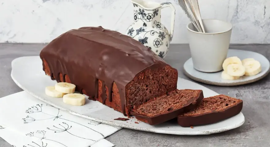 Saftige Schoko-Bananen-Torte mit dunkler Schokoladenglasur, garniert mit Bananenscheiben. Ein Genuss für jeden Kaffeetisch.