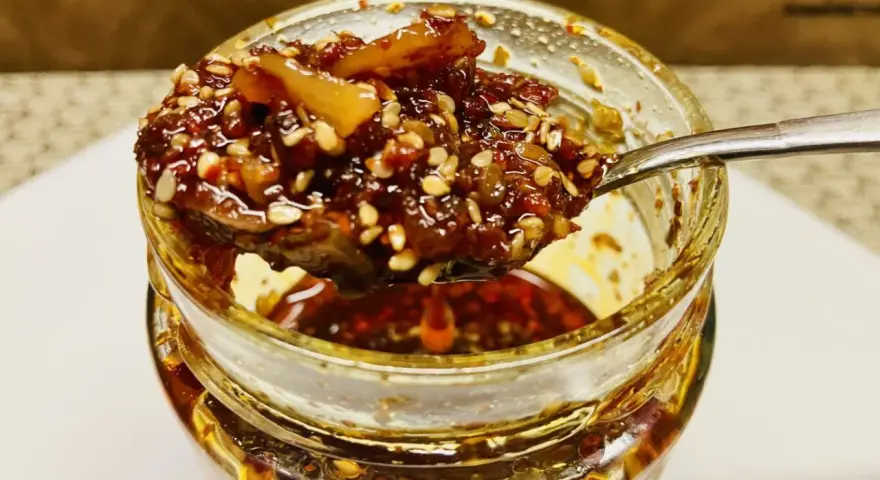 Ein Löffel voller knusprigem Chiliöl mit Sesam und Gewürzen, bereit, Gerichte zu verfeinern.