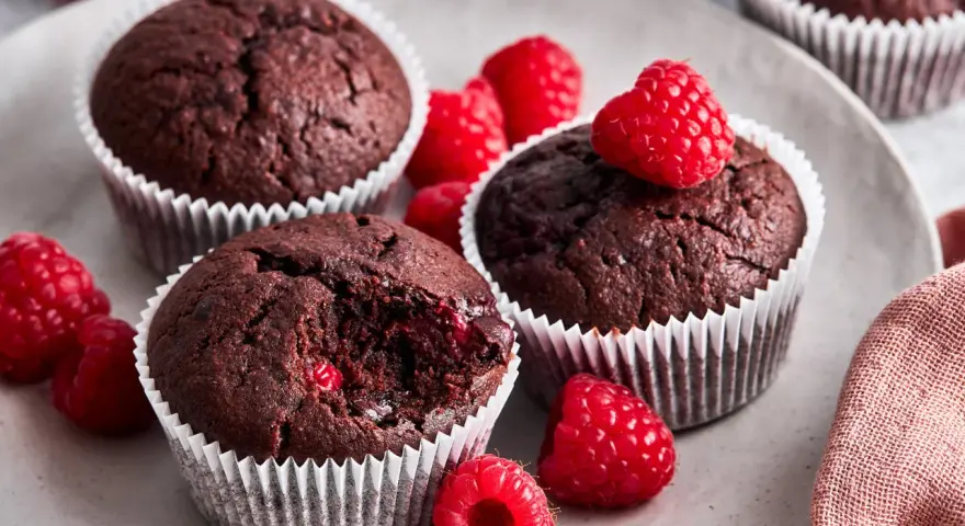 Saftige schoko himbeer muffins auf einem Teller, garniert mit frischen Himbeeren. Ein Genuss für alle Sinne!