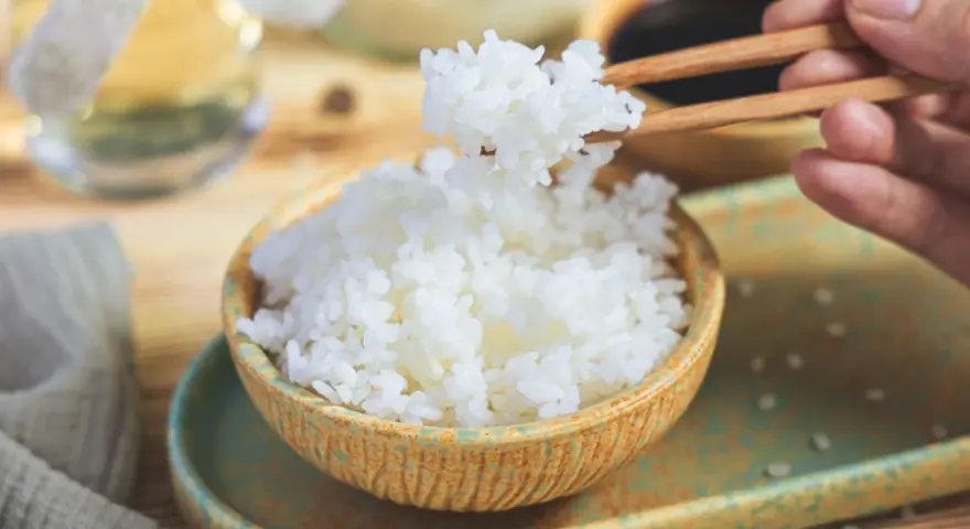 Perfekter sushi reis im reiskocher, dampfend und bereit, mit Stäbchen gegriffen zu werden. Ein Hauch von Asien auf dem Tisch.