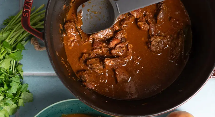 Herzhaftes Gulasch im Gusseisentopf, das beste Gulasch Rezept original Oma. Mit Petersilie und Zwiebeln.