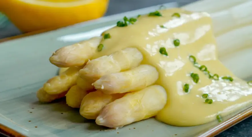 Spargel mit cremiger Sauce Hollandaise, garniert mit Schnittlauch. Ein Klassiker der Frühlingsküche.