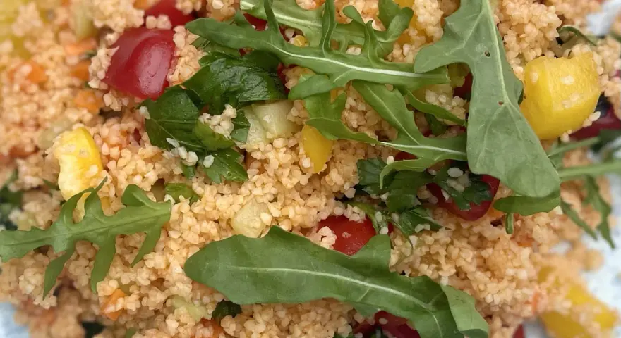 Frischer Couscous-Salat mit Tomaten, Gurken, Paprika und Rucola. Ein leichter und gesunder Genuss.