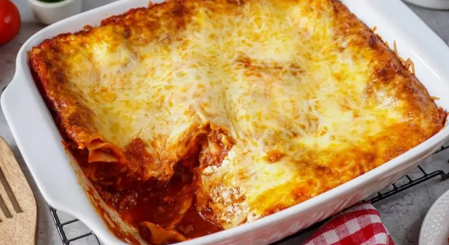 Herzhafte Lasagne mit Schmand und goldbraun überbackenem Käse in einer weißen Auflaufform.