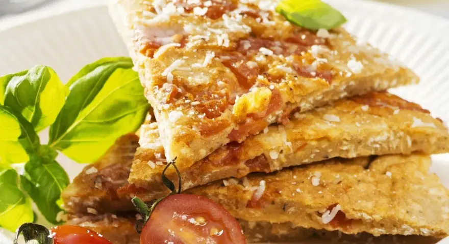 Herzhafte Hauptspeise: knusprige Eierkuchen-Schnitten mit Tomaten und Parmesan, garniert mit Basilikum und Kirschtomaten.