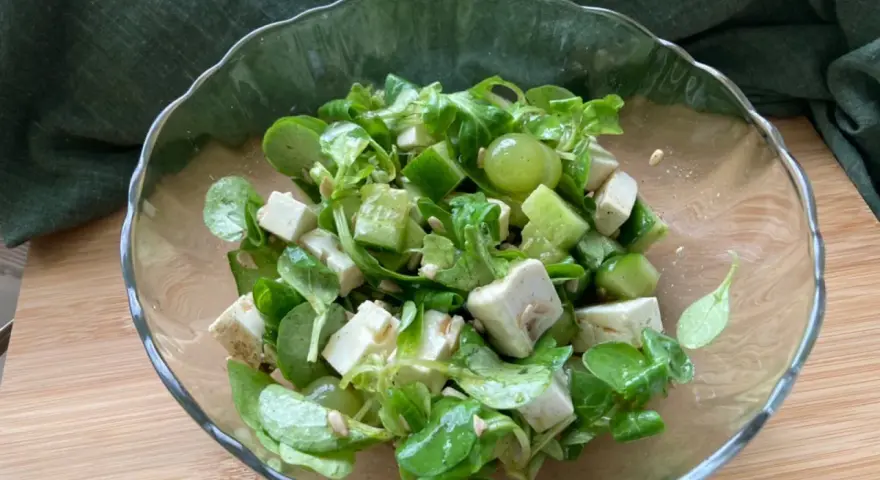 Erfrischender weintrauben feta salat mit Gurkenwürfeln und Sonnenblumenkernen in einer Glasschüssel.