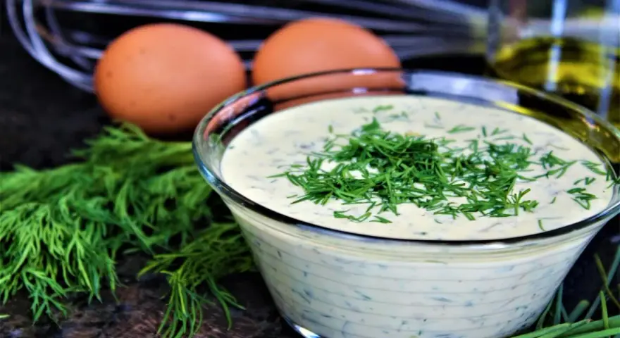 Schüssel mit cremiger Remoulade, garniert mit Dill. Eier und Kräuter deuten auf ein authentisches Remoulade Rezept Original hin.
