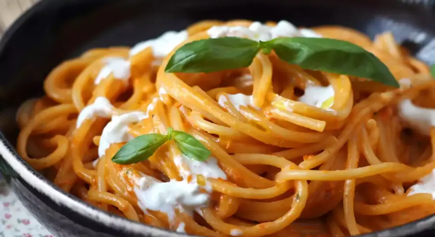 Spaghetti mit cremiger Tomatensoße und frischer Burrata, garniert mit Basilikum. Ein Genuss für alle Liebhaber von Pasta.