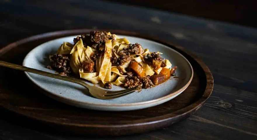 Teller mit breiten Bandnudeln und herzhafter Hackfleischsauce, eine köstliche spaghetti bolognese.