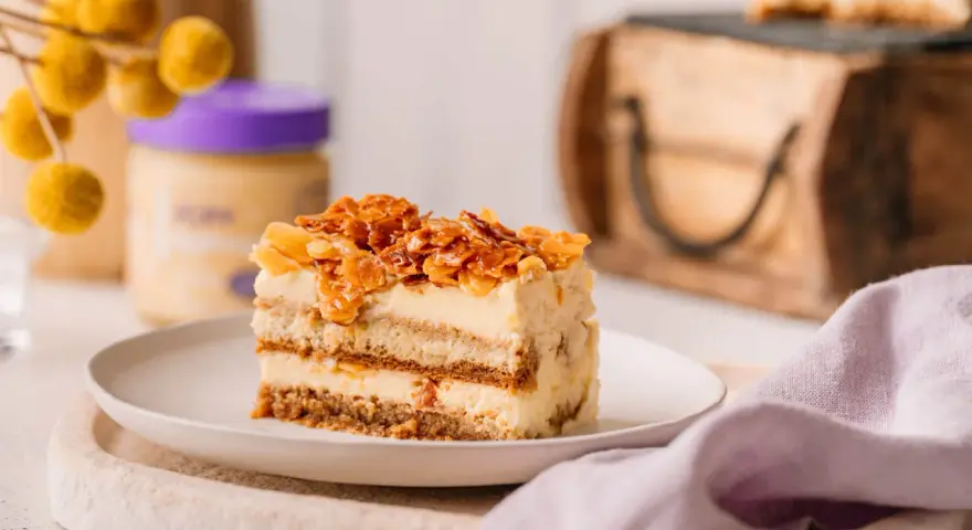 Ein Stück Bienenstich Tiramisu mit karamellisierten Mandeln und cremiger Füllung auf einem Teller.