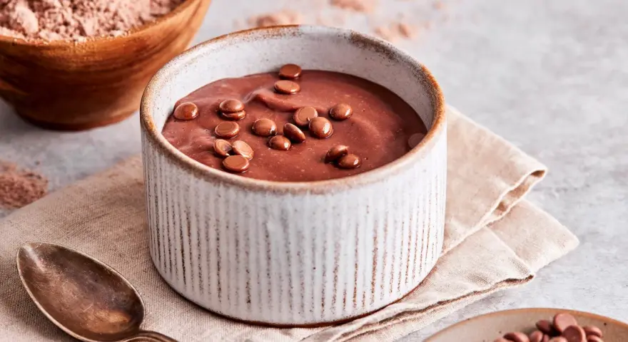 Schokoladenpudding, frisch zubereitet, mit Schokostückchen garniert. Perfekt, um Pudding selber machen zu lernen.