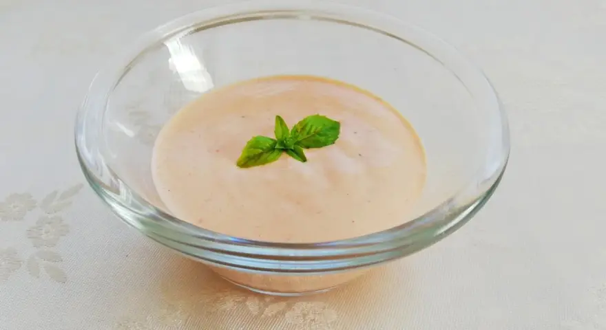 Cremiges Sugo Aurora in einer Glasschale, garniert mit frischem Basilikum.