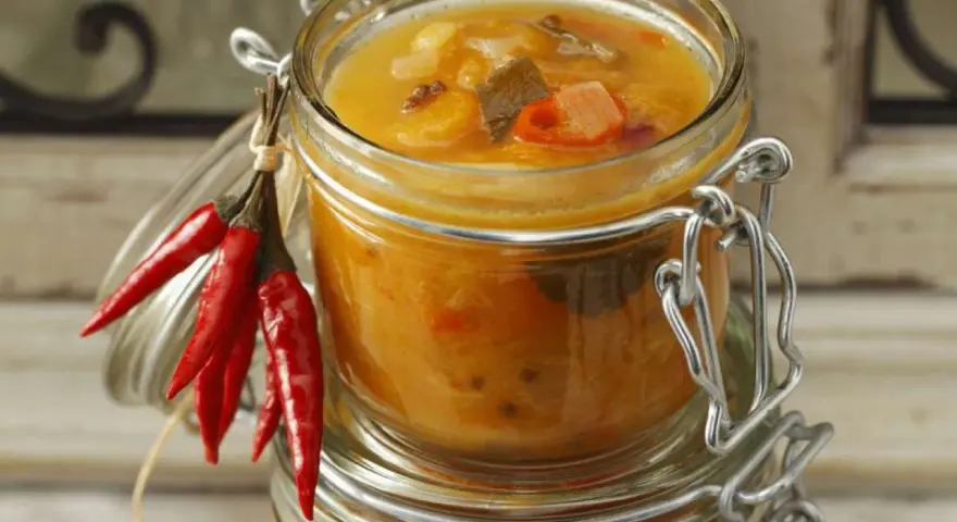 Ein Glas mit leckerem Aprikosen-Chutney-Rezept, garniert mit roten Chilis. Perfekt für herzhafte Gerichte.