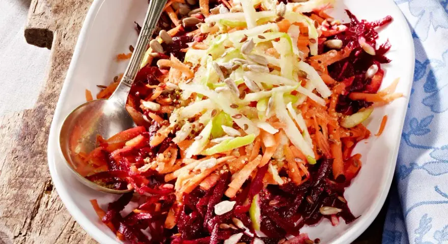 Bunter Salat aus geraspelter roter Bete, Karotten und Apfel, garniert mit Sonnenblumenkernen.