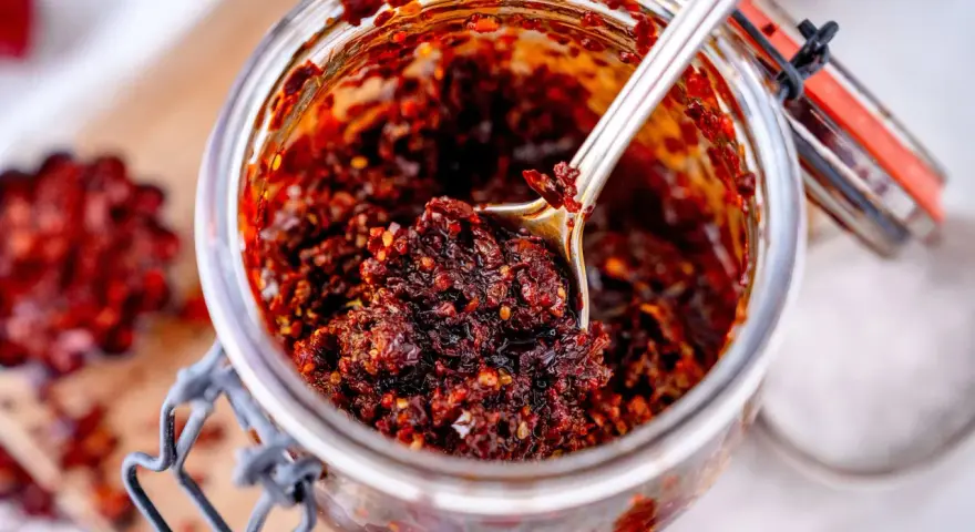 Ein Glas mit würzigem Chili Crunch, perfekt für jedes Chili Crunch Rezept. Eine Löffelspitze voller Geschmack!