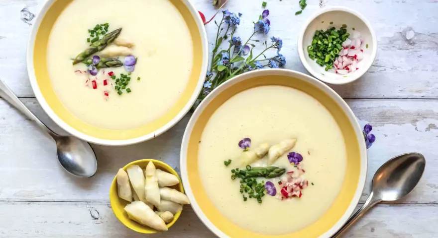 Cremige Spargelsuppe, ein einfaches Rezept für den Frühling. Garniert mit Spargelspitzen, Radieschen und Schnittlauch.