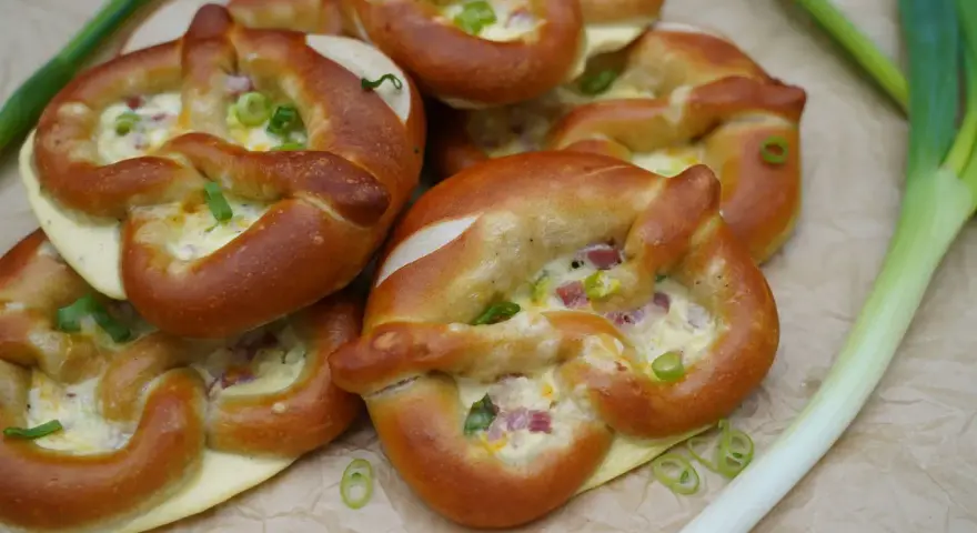 Herzhafte Brezeln gefüllt mit Käse und Speck, perfekt als partyrezepte aus dem ofen zum vorbereiten. Mit Frühlingszwiebeln garniert.