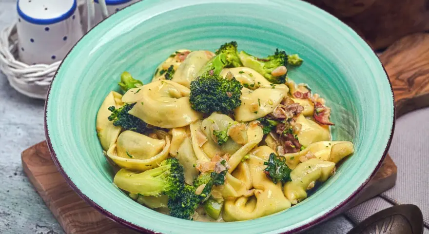Eine Schüssel mit Tortellini in cremiger Sauce, garniert mit Brokkoli und Speck. Perfekt für eine schnelle Sauce zu Tortellini.