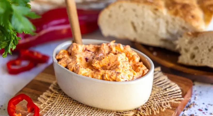 Cremiger Ajvar Feta Dip mit frischer Petersilie und Paprika, serviert mit rustikalem Brot.