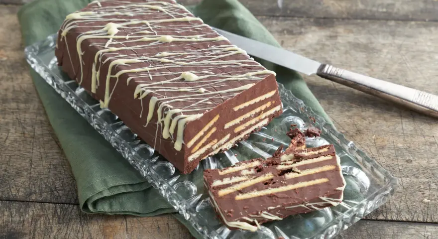 Kalter Hund mit Schokolade und Sahne: Ein Schichtkuchen aus Keksen und Schokomasse, verziert mit weißer Schokolade.