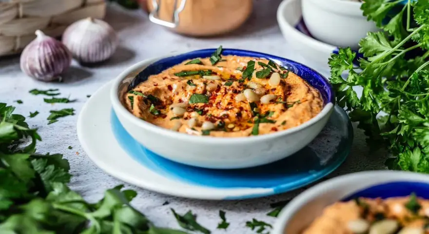 Cremiger Feta Paprika Dip mit Pinienkernen und frischer Petersilie, garniert mit Chiliflocken. Perfekt zum Dippen!