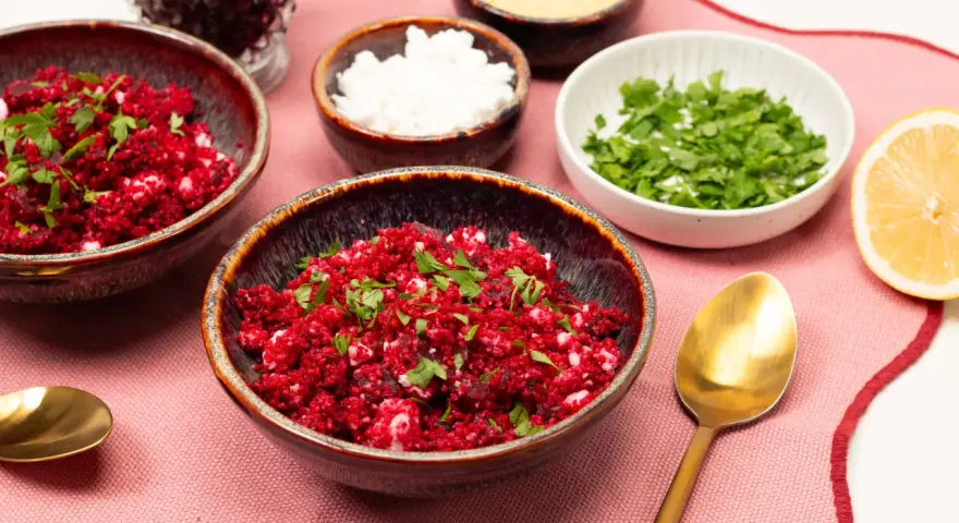 Rote Bete Couscous Salat mit Feta und Petersilie, garniert mit Zitronenspalte.