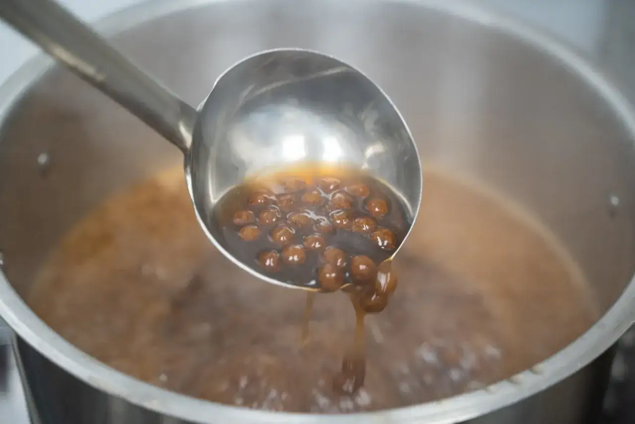 Eine Sch&ouml;pfkelle hebt kochende tapioka perlen selber machen aus einem Topf.