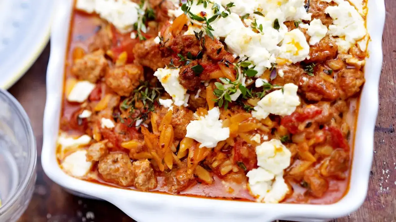 Herzhafter Kritharaki Auflauf mit Hackfleischb&auml;llchen, Tomaten und zerbr&ouml;ckeltem Feta, garniert mit frischen Kr&auml;utern.