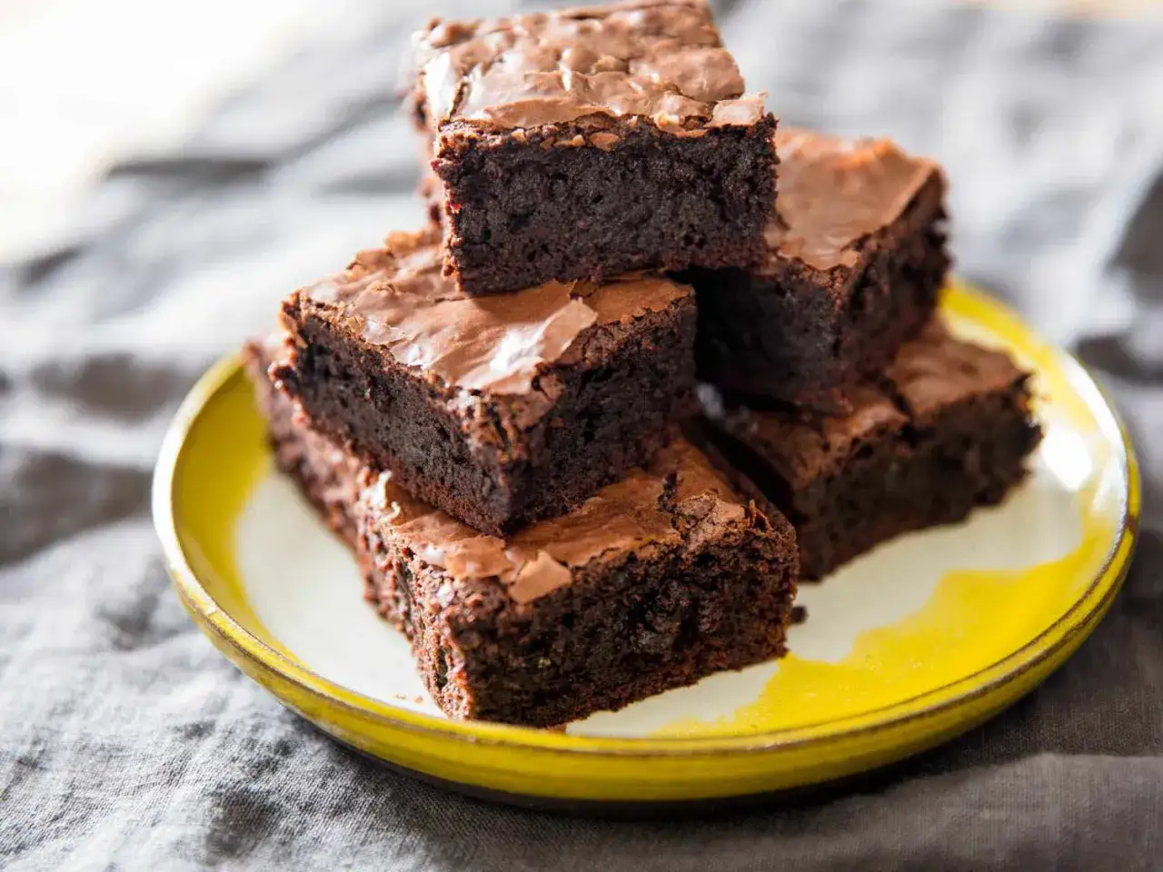 Ein Stapel saftiger Schokoladenbrownies auf einem Teller. Dieses brownie rezept ist einfach und gelingt immer.