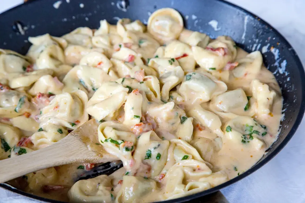 Eine Pfanne voller cremiger Tortellini mit einer schnellen Sauce, verfeinert mit Kr&auml;utern und Tomatenst&uuml;cken. Ein k&ouml;stliches Gericht, das im Handumdrehen zubereitet ist.