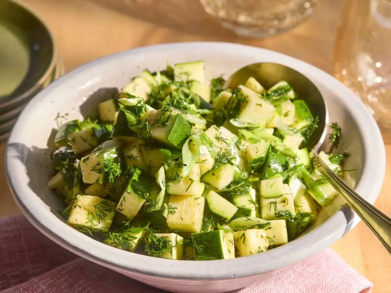 Frischer Zucchini-Salat mit Dill, serviert in einer Sch&uuml;ssel mit einem L&ouml;ffel.