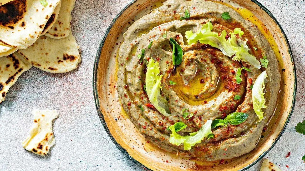 Cremiges Baba Ganoush, garniert mit Oliven&ouml;l, Paprikapulver und frischen Kr&auml;utern, serviert mit warmem Fladenbrot.