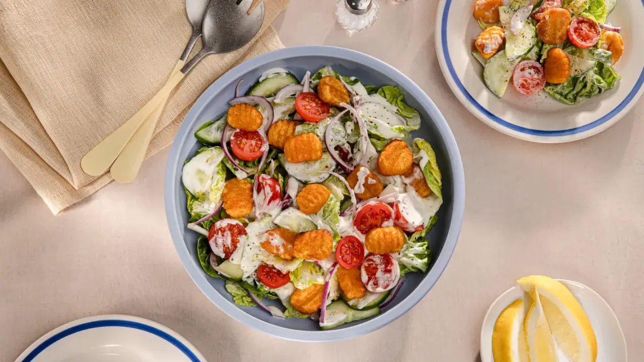 Frischer Salat mit knackigem Salat, Tomaten, Gurken, roten Zwiebeln und knusprigen Gnocchi-St&uuml;ckchen, betr&auml;ufelt mit cremiger So&szlig;e.