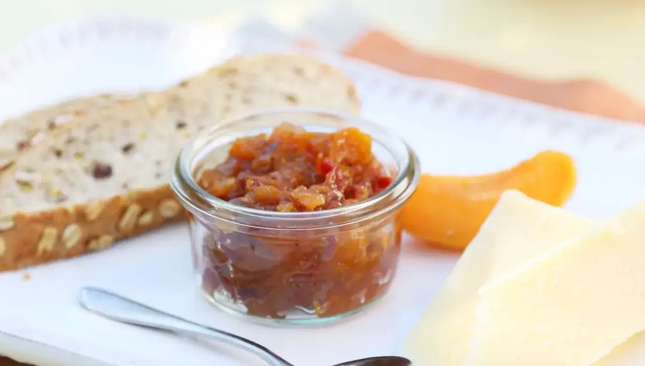 Ein Glas mit leckerem Aprikosen-Chutney, serviert mit Brot und K&auml;se. Perfekt f&uuml;r ein Aprikosen-Chutney-Rezept.